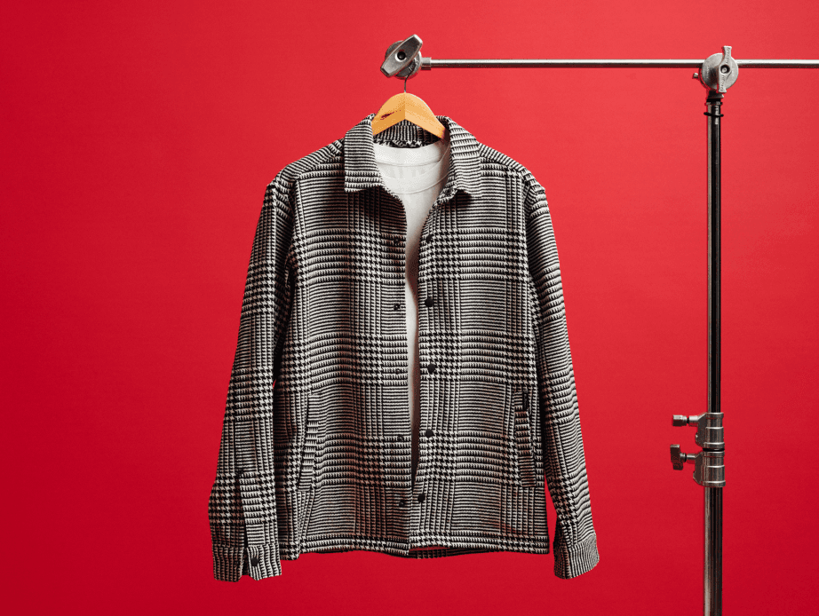 A black-and-white plaid jacket hanging in front of a red background